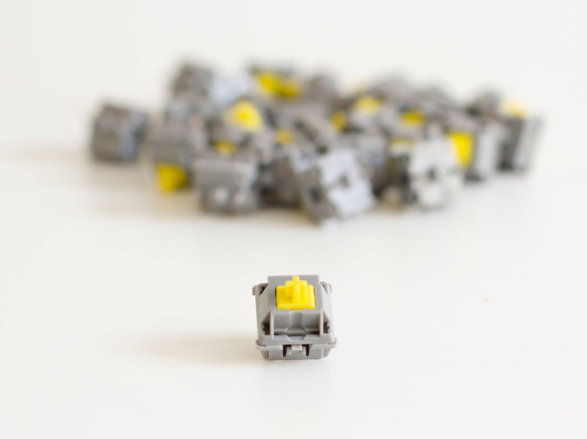 A batch of JWK Durock tactile POM T1 sunflower mechanical keyboard switches with one switch at the front.